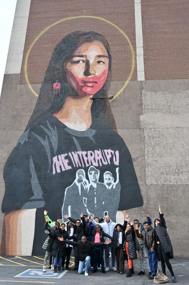 A group of 13 delegates pose in front of Gregg Deal's mural: Take Back the Power during a Downtown Colorado Springs Art Walk!